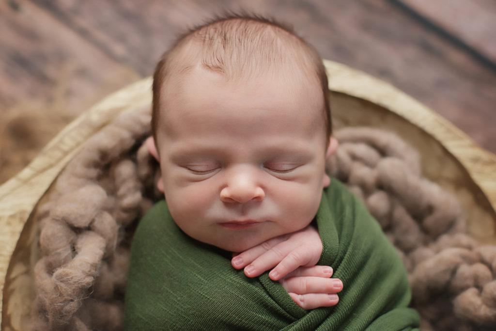 Baby boy swaddled with his hands together sweetly.